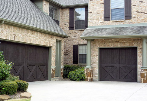 Exterior of brown brick house with freshly painted garage doors