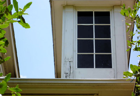 Exterior of attic window with peeling white paint