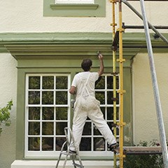 Man on scaffold painting exterior of building