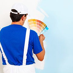 Man holding paint swatches in front of a white wall