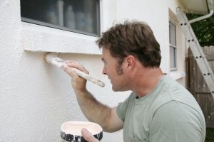 A man painting the exterior of a house.