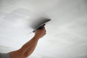 A man smoothing out a ceiling.