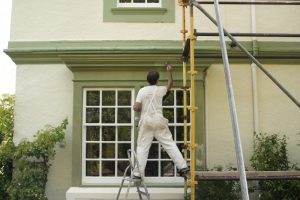 a professional painter painting trim on the outside of a house
