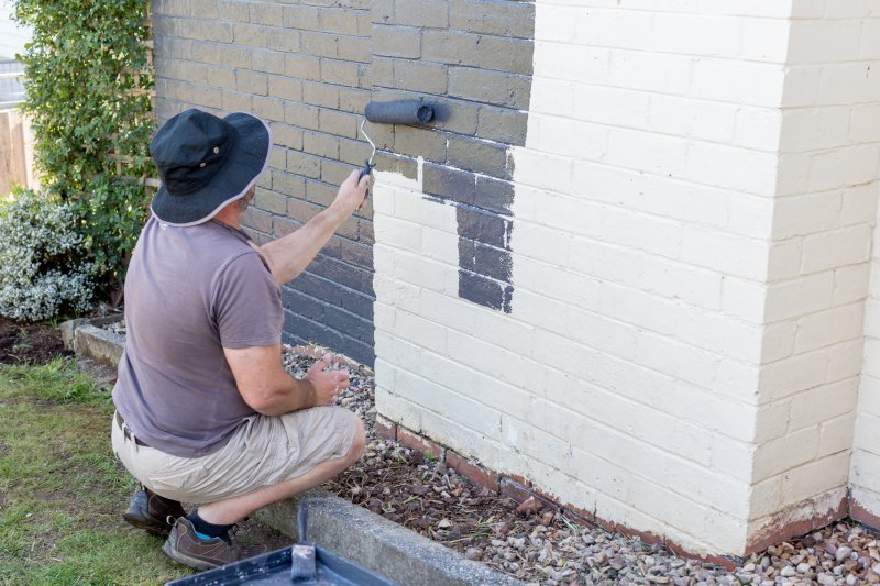man painting exterior brick