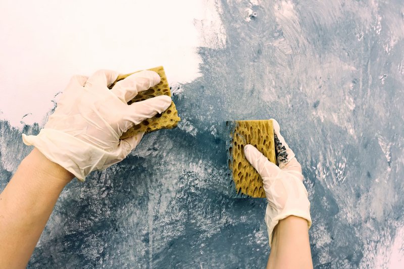 man painting sponge wall