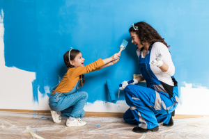 a woman and her daughter painting a wall together 
