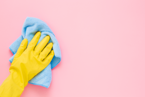 a gloved hand washing a pink wall