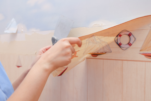 a person removing old wallpaper