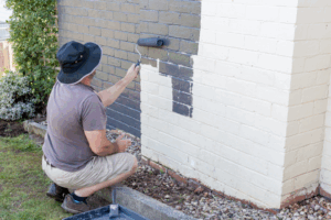 a person painting their brick house