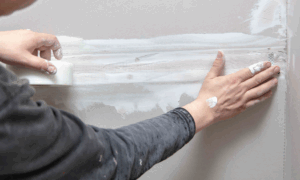 a person inspecting and repairing damage to drywall